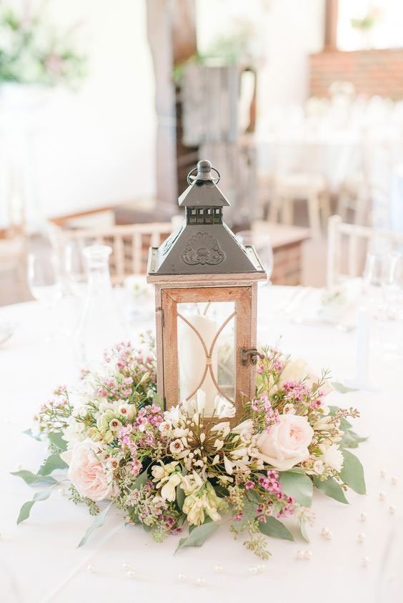 Centre de table mariage rustique avec lanterne facon bois entourée de fleurs